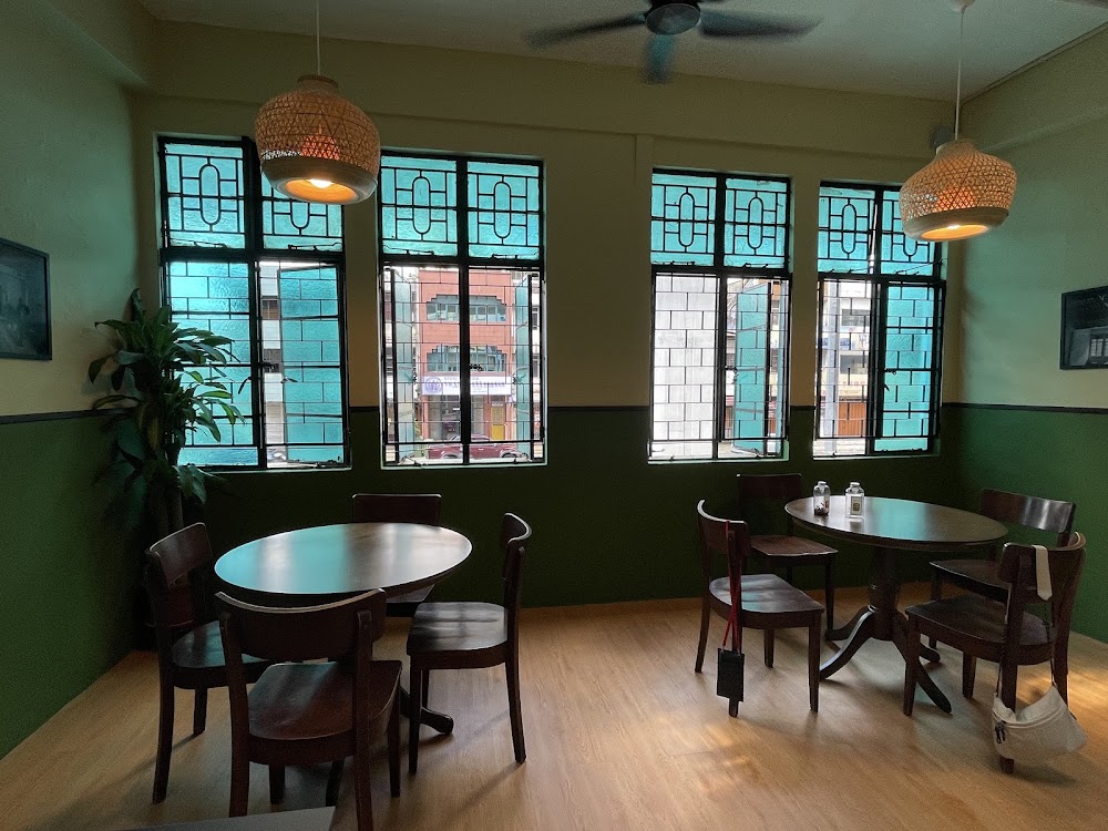 Emerald-walled dining room with turquoise steel-grid windows, rattan pendant lamps and wooden tables
