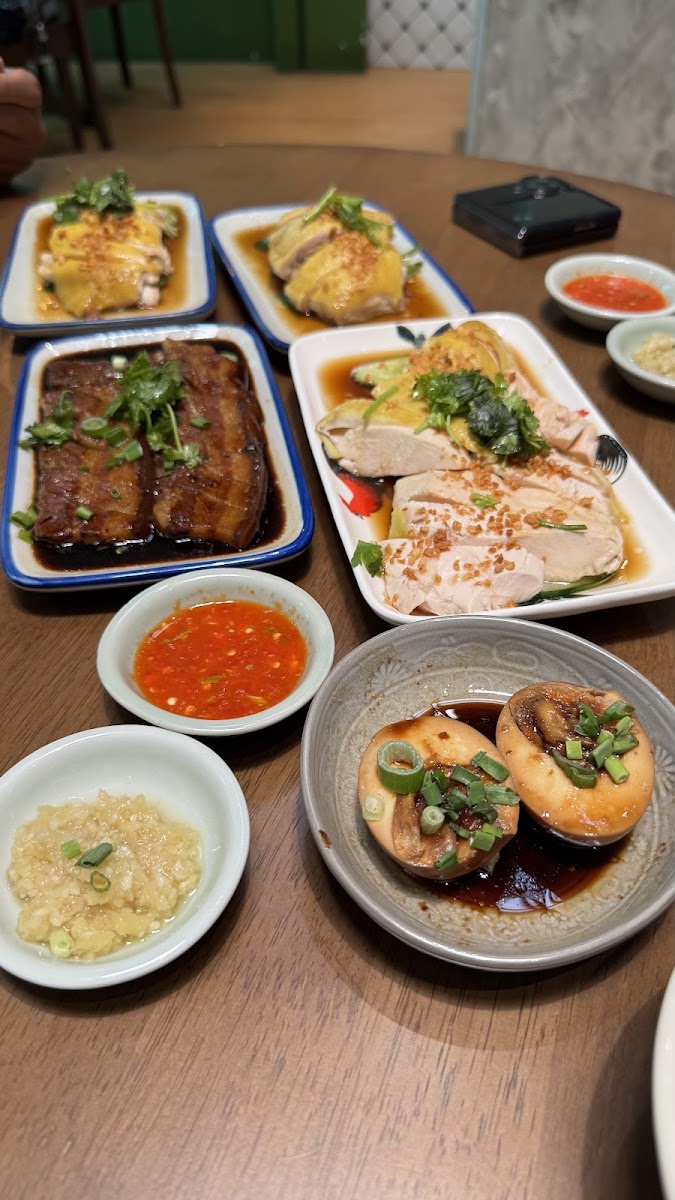 A spread of chicken, braised pork belly and soy-braised eggs on blue-rim plates